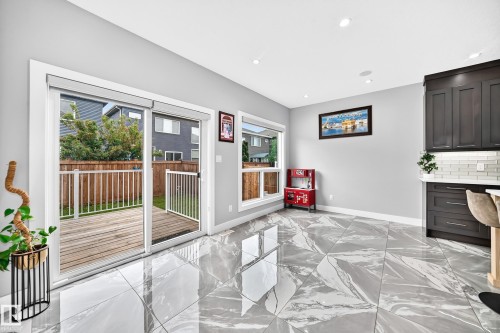 Spacious indoor-outdoor living area featuring large format, high-gloss tile flooring with a marble-like pattern - 8710 Mayday Lane, Edmonton, AB 
