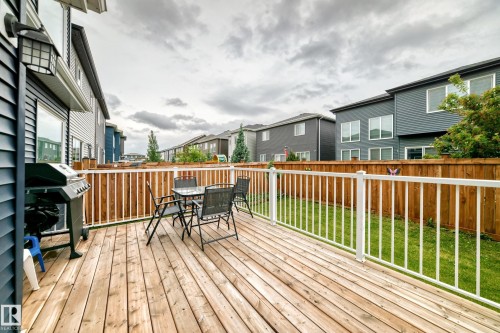 Spacious backyard deck featuring natural wood decking, white railing, and a private wood fence - 8710 Mayday Lane, Edmonton, AB 