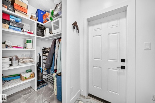 Recessed storage closet featuring custom built-in shelving, hanging rod, and a gray-toned tile floor - 8710 Mayday Lane, Edmonton, AB 
