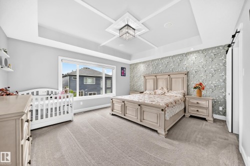 Spacious room featuring a tray ceiling with recessed lighting, a modern chandelier, and light gray wall paint - 8710 Mayday Lane, Edmonton, AB 