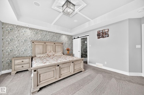 Bedroom featuring a patterned accent wall, coffered ceiling, and recessed lighting - 8710 Mayday Lane, Edmonton, AB 