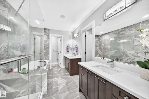 Spacious bathroom featuring large format gray marble-look tile flooring and wall accents - 8710 Mayday Lane, Edmonton, AB 