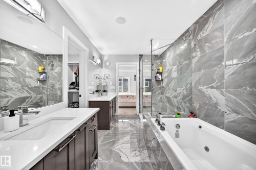 Spacious bathroom featuring marble-look tile flooring and wall accents - 8710 Mayday Lane, Edmonton, AB 