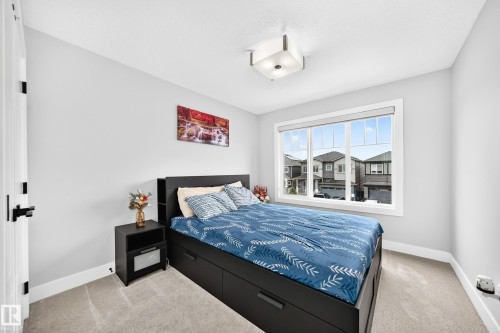 Bright room featuring a large window, light gray walls, and textured carpet flooring - 8710 Mayday Lane, Edmonton, AB 