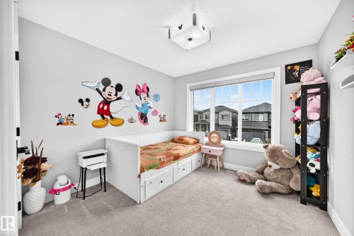 Carpeted room with a large window featuring white trim and a roller shade - 8710 Mayday Lane, Edmonton, AB 