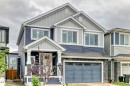 Contemporary two-story exterior featuring blue horizontal siding, light grey vertical siding, and a stone facade - 8710 Mayday Lane, Edmonton, AB 