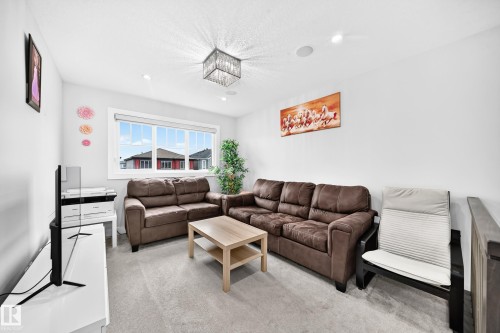 Carpeted living space featuring recessed lighting and a contemporary chandelier - 8710 Mayday Lane, Edmonton, AB 