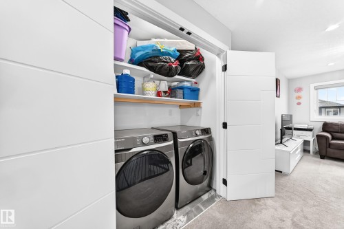 Dedicated laundry closet with front-loading washer and dryer, featuring built-in shelving - 8710 Mayday Lane, Edmonton, AB 
