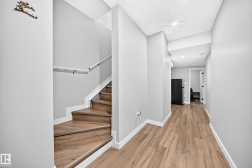 Wood-finish flooring throughout, featuring a staircase with white risers and a white handrail - 8710 Mayday Lane, Edmonton, AB 