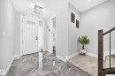 Foyer featuring a white front door with transom and sidelight, large format gray marble-look tile flooring, and a contemporary crystal flush mount light fixture - 8710 Mayday Lane, Edmonton, AB 