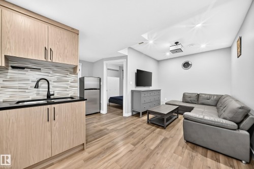 Kitchenette featuring light wood-finish cabinetry, black countertops, and a tiled backsplash - 8710 Mayday Lane, Edmonton, AB 