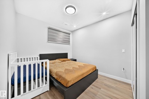 Bedroom with wood-finish flooring, neutral wall tones, and a window featuring roller blinds - 8710 Mayday Lane, Edmonton, AB 