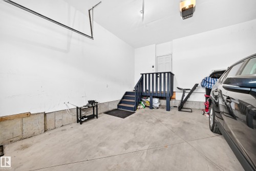Spacious garage featuring concrete flooring and a white painted interior - 8710 Mayday Lane, Edmonton, AB 