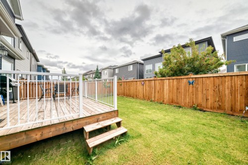 Outdoor wood deck with white railing, featuring a multi-level design and direct access to a spacious green lawn - 8710 Mayday Lane, Edmonton, AB 