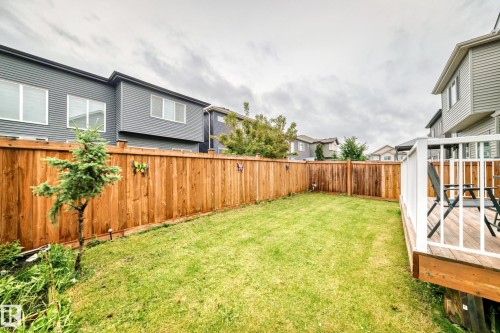Fenced backyard featuring a manicured lawn, a privacy fence, and a wooden deck with white railings - 8710 Mayday Lane, Edmonton, AB 