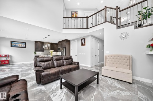 Open-concept living area featuring a two-story ceiling and contemporary marble-finish tile flooring - 8710 Mayday Lane, Edmonton, AB 