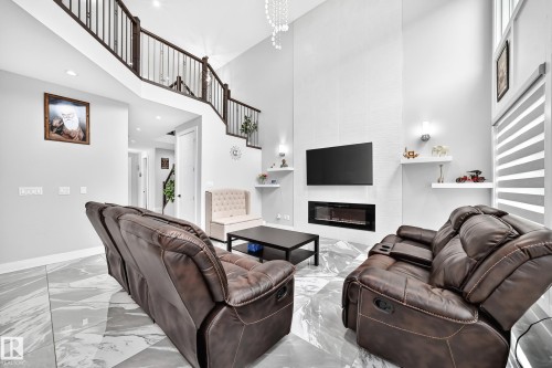 Two-story living area with high ceilings and a prominent staircase featuring dark wood newel posts and balusters - 8710 Mayday Lane, Edmonton, AB 