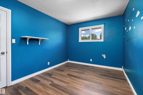 Interior room featuring wood-finish flooring, white baseboards, and a single window with white trim - 5516 47A Avenue, Wetaskiwin, AB - Indoor Photo Showing Other Room