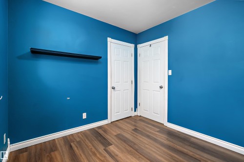 Vibrant blue walls complemented by wood-finish flooring - 5516 47A Avenue, Wetaskiwin, AB - Indoor Photo Showing Other Room