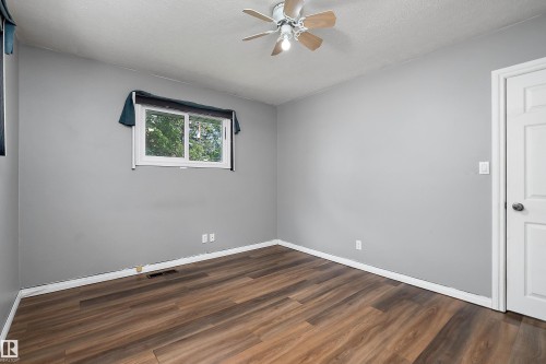 Room featuring wood-finish flooring, a ceiling fan, light gray wall paint, white trim, and a white interior door - 5516 47A Avenue, Wetaskiwin, AB - Indoor Photo Showing Other Room