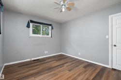 Room featuring wood-finish flooring, a ceiling fan, light gray wall paint, white trim, and a white interior door - 