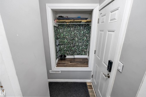 Entryway closet featuring botanical-patterned wallpaper and wood-finish flooring - 5516 47A Avenue, Wetaskiwin, AB - Indoor Photo Showing Other Room