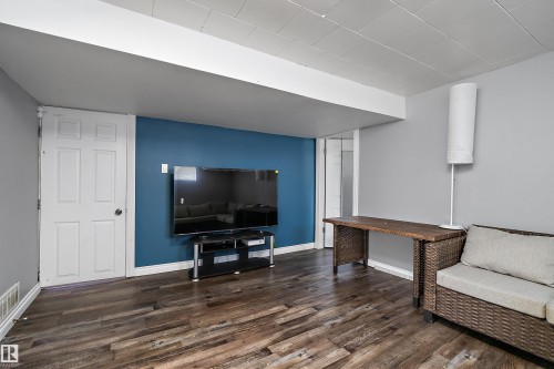 Spacious interior featuring wood-finish flooring, a vibrant accent wall, white painted trim, and a white paneled door - 5516 47A Avenue, Wetaskiwin, AB - Indoor Photo Showing Other Room