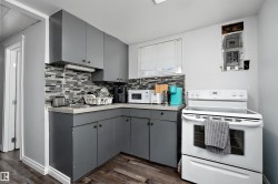 Compact kitchen featuring grey cabinetry, a mosaic tile backsplash, a white electric range, and wood-finish flooring - 