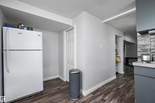 Wood-finish flooring throughout, complemented by a contemporary tile backsplash and light gray walls - 5516 47A Avenue, Wetaskiwin, AB - Indoor Photo Showing Kitchen