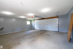 Spacious garage featuring a concrete floor, light gray walls, white ceiling, and a white overhead garage door with an automatic opener - 