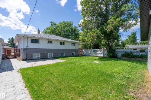 Spacious backyard featuring a substantial lawn, mature trees, a paved patio area, and a raised garden bed - 5516 47A Avenue, Wetaskiwin, AB - Outdoor