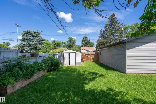 Expansive backyard featuring a lush lawn, a storage shed, a raised garden bed, and a detached building with horizontal siding - 5516 47A Avenue, Wetaskiwin, AB - Outdoor