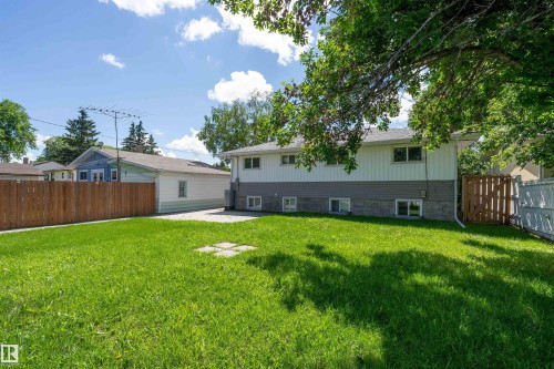 Expansive rear yard featuring a manicured lawn, established perimeter fencing, and mature trees providing natural shade - 5516 47A Avenue, Wetaskiwin, AB - Outdoor