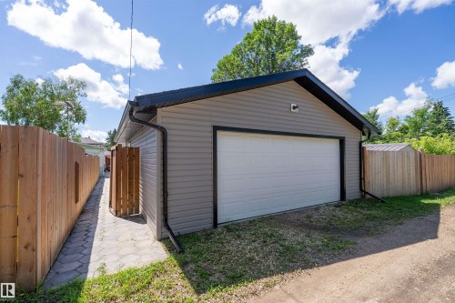 Detached garage with horizontal siding, a white overhead door, and a dark shingled roof - 5516 47A Avenue, Wetaskiwin, AB - Outdoor