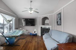 Spacious room featuring vaulted ceilings, wood-finish flooring, a wall-mounted television, and a fireplace with an arched niche - 