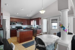 Spacious kitchen featuring rich wood cabinetry, dark countertops, a central island, and recessed lighting - 