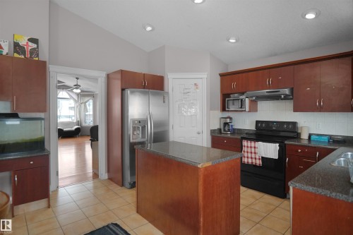 Kitchen featuring wood-finish cabinetry and a central island with a stone-finish countertop - 4816 155 Ave, Edmonton, AB 