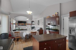 Kitchen featuring a central island with a granite-style countertop, mahogany-finish cabinetry, and ceramic tile flooring - 