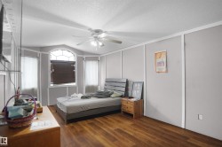 Room featuring wood-finish flooring, a ceiling fan with integrated lighting, and multiple windows - 