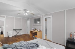 Spacious room with wood-finish flooring, ceiling fan, and light gray paneled walls with white trim - 