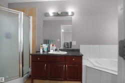Bathroom featuring a glass-enclosed shower, a built-in corner bathtub, and a vanity with a dark countertop and wood-finish cabinetry - 