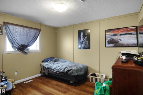 Bedroom featuring wood-finish flooring, a single window, and a ceiling-mounted light fixture - 4816 155 Ave, Edmonton, AB 