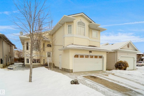 Two-story home with a two-car garage, bay window, arched window details, and a paved driveway - 4816 155 Ave, Edmonton, AB 