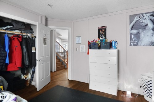 Room featuring wood-finish flooring, light grey walls, white trim, and a white six-drawer dresser - 4816 155 Ave, Edmonton, AB 