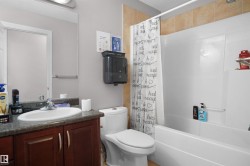 Bathroom featuring a vanity with dark wood-finish cabinetry, a white basin sink, and a speckled countertop - 