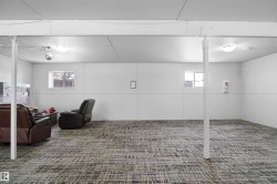 Spacious lower level featuring patterned carpet flooring, two windows, recessed lighting, and white support columns - 
