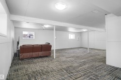Spacious room featuring patterned carpet flooring, white paneled walls, multiple windows, and flush-mount lighting fixtures - 