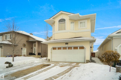 Two-story property featuring a front-facing attached garage, a bay window with an arched transom, and light-colored siding - 4816 155 Ave, Edmonton, AB 