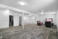 Expansive finished lower level featuring patterned carpet, white paneling, and ceiling-mounted dome lighting - 