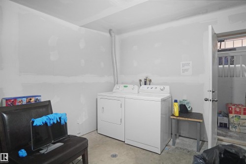 Dedicated laundry area featuring a washer and dryer, concrete flooring, and unfinished walls - 4816 155 Ave, Edmonton, AB 